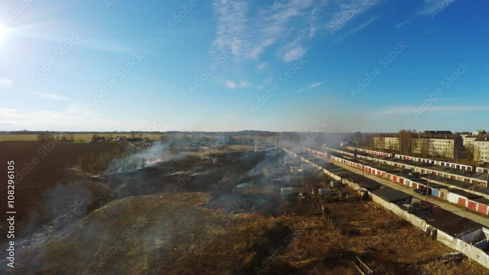 Perspective of burning grass close to garages and cars. Aerial footage. Perspective of burning grass close to garages and cars. Aerial footage.