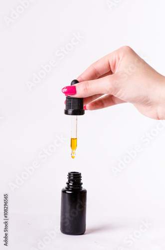 Drops from a dropper in a bottle. Isolated on a white background. Pharmacy and healthy background. Medicine. . Woman´s hand keep a dropper