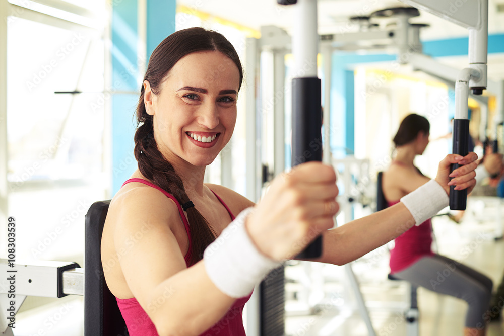 Girl is working out on butterfly machine in gym