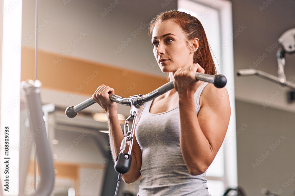 Strong woman weightlifting at the gym looking happy and working