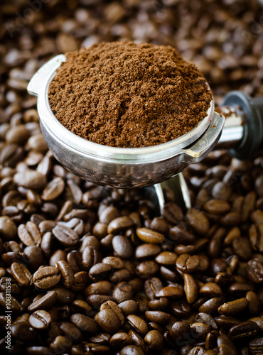 Ground coffee in brew unit on coffee bean background photo