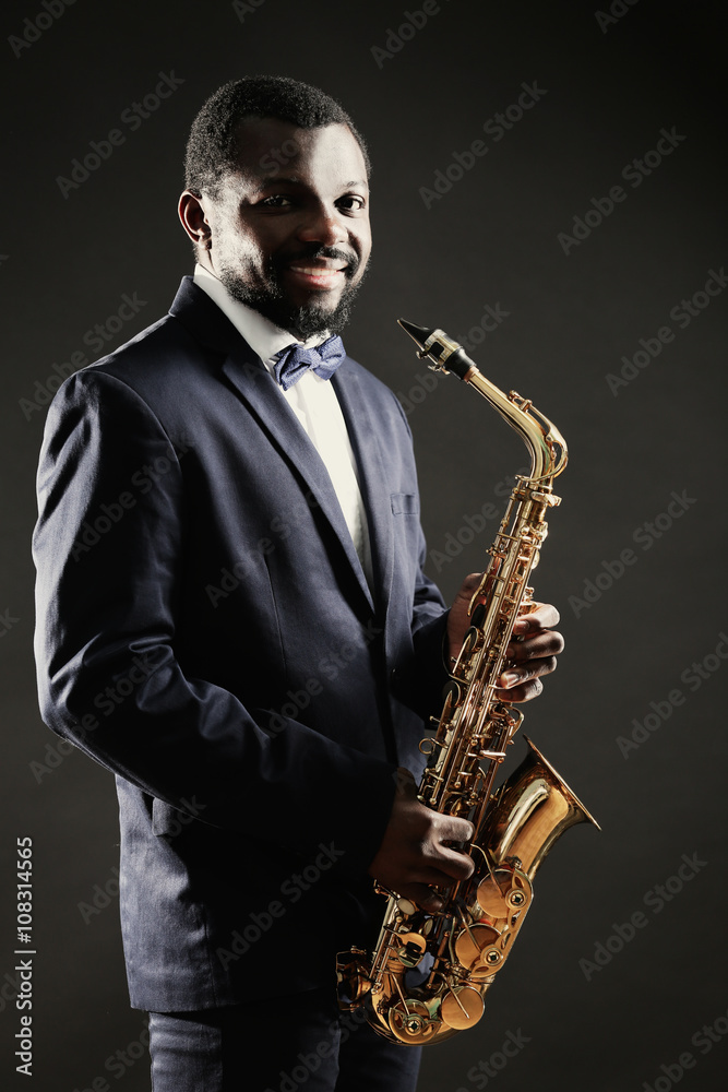 Fototapeta premium African American jazz musician playing the saxophone on grey background