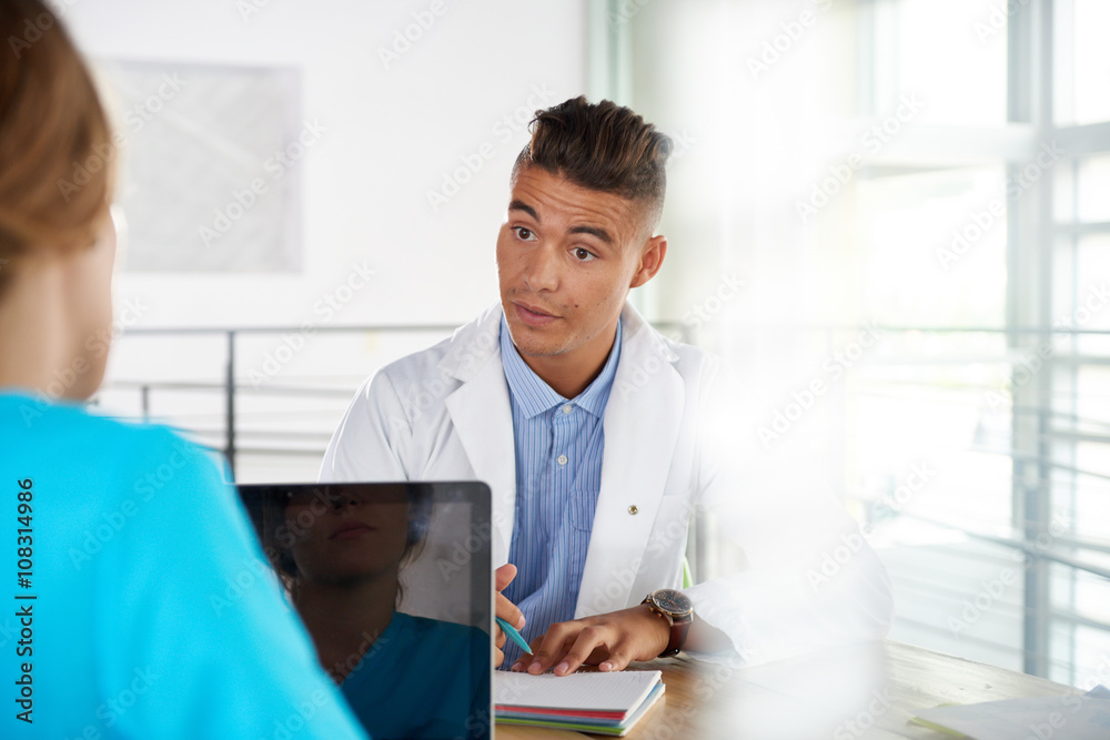 Obraz premium Team of doctor and nurse discussing a patient diagnosis sitting at the desk in bright modern office