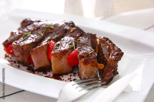 Sliced roasted pork steak with fork on white plate