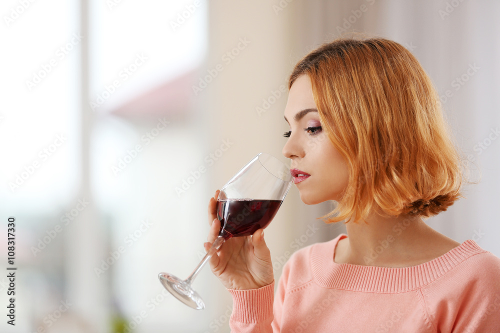 Young woman with glass of red wine on light blurred background Young woman with glass of red wine on light blurred background