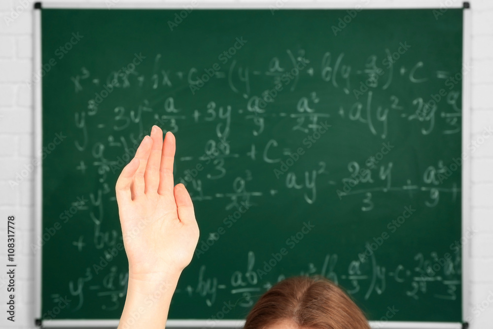 Raised hand on blackboard background in class Raised hand on blackboard background in class