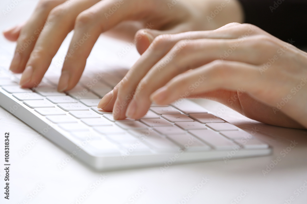 Female hands using keyboard on white wooden table, close up Female hands using keyboard on white wooden table, close up