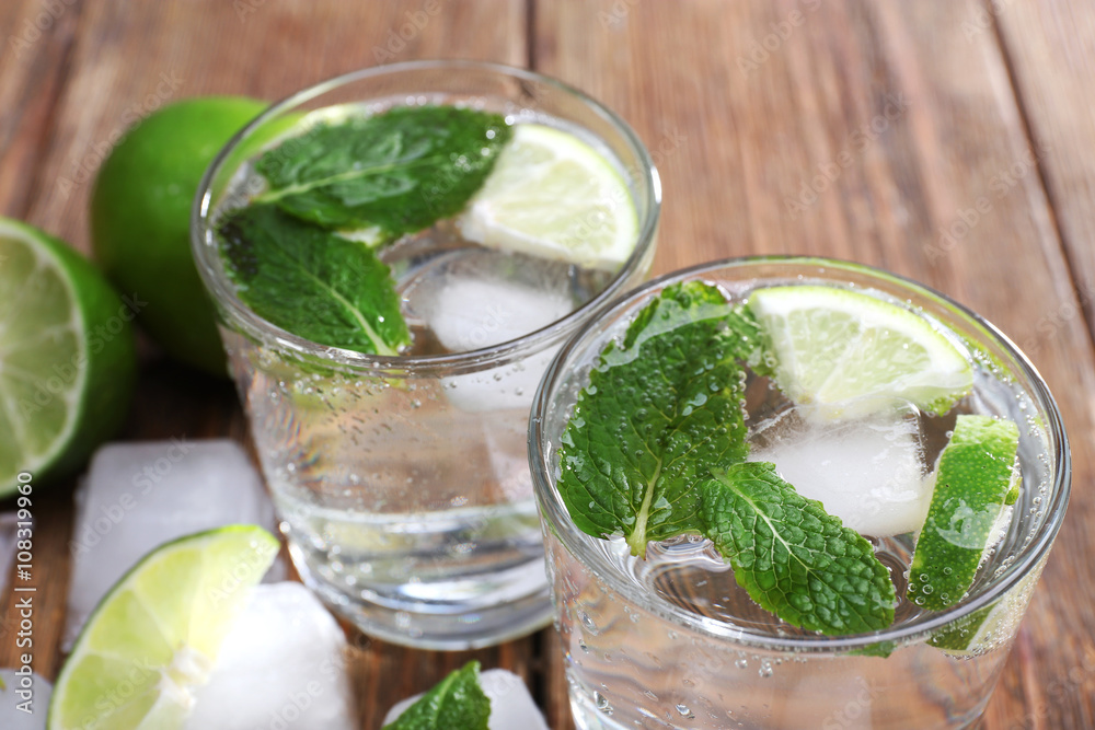 Fresh cocktails with mint, ice and lime on wooden table background Fresh cocktails with mint, ice and lime on wooden table background