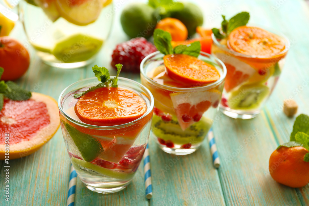 Refreshing cocktails with ice, mint, pomegranate seeds and slices of fruits on blue wooden background Refreshing cocktails with ice, mint, pomegranate seeds and slices of fruits on blue wooden background