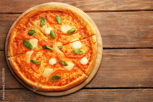 Sliced Margherita pizza on wooden background