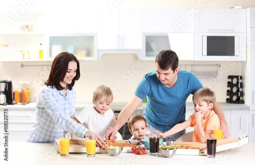 Happy family eating pizza in the kitchen together