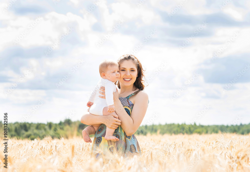 Beautiful woman playing with her infant baby in a meadow of whea Beautiful woman playing with her infant baby in a meadow of whea