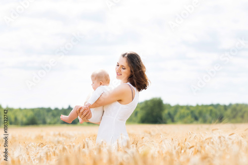 Beautiful woman playing with her infant baby in a meadow