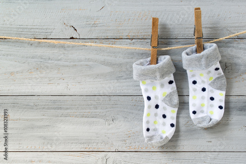 Baby socks hanging on clothesline on wooden background