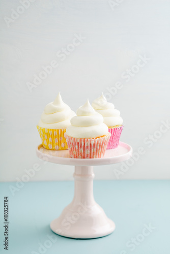 Three cupcakes with buttercream frosting on a cake stand