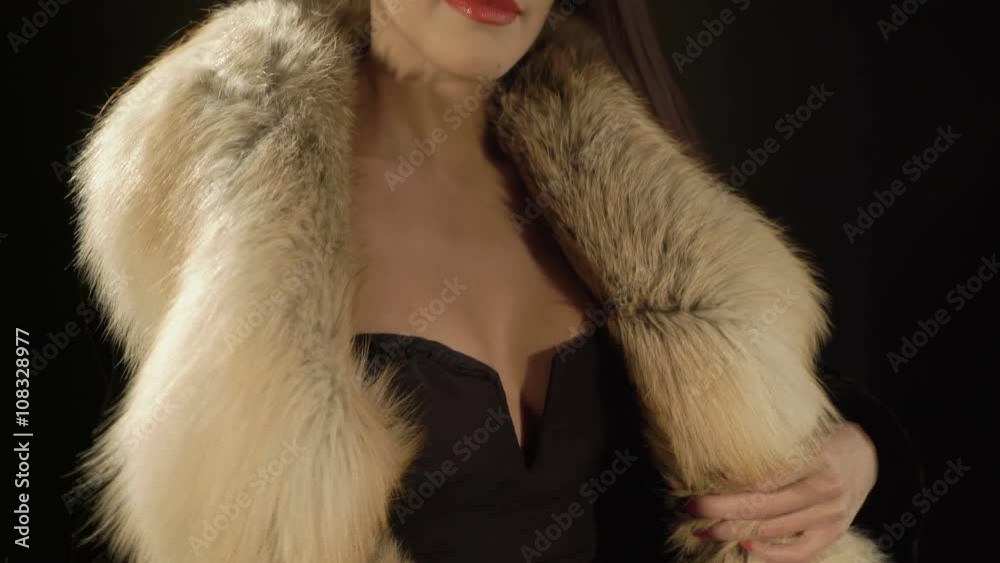 Attractive young woman posing in elegant fur jacket and sexy evening black v neck bodycon dress looking at camera, jib moving up Attractive young woman posing in elegant fur jacket and sexy evening black v neck bodycon dress looking at camera, jib moving up