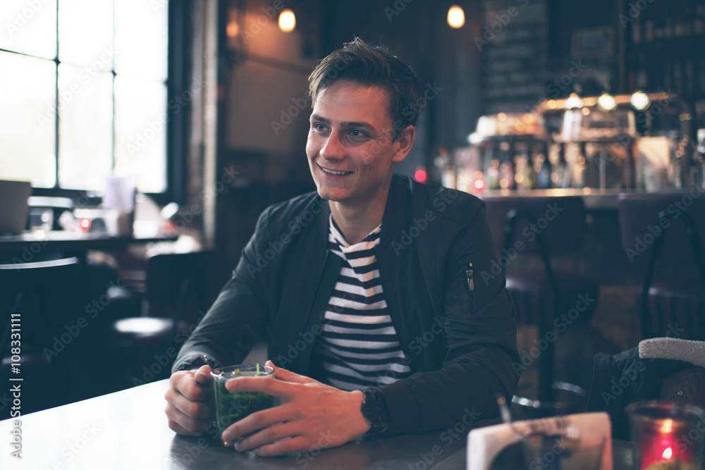 Smiling man sitting at table in bar enjoying fresh mint tea Smiling man sitting at table in bar enjoying fresh mint tea