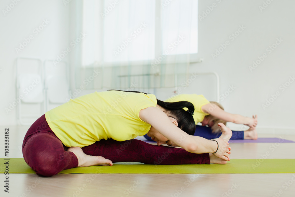 women practicing Janu Sirsasana (Head-to-Knee Pose)