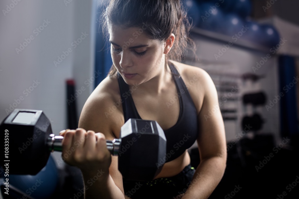 Woman exercise with dumbbells and working on her biceps Woman exercise with dumbbells and working on her biceps