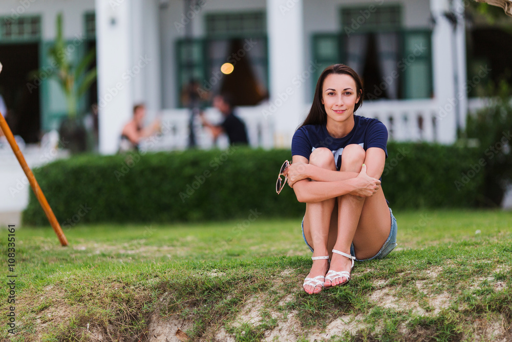 Fototapeta premium Young girl sitting on the grass, evening, summer, holiday