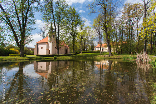 Small church is reflected on the surface of the pond in the park