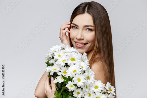 Beautiful Woman with Clean Fresh Skin holding flowers