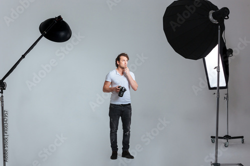 Quadro su tela Pensive male photographer standing in professional studio