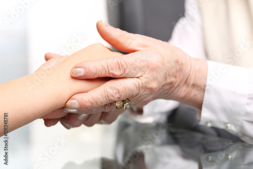 Pomocna dłoń.
Dłoń starszej kobiety przytula dłoń dziecka
