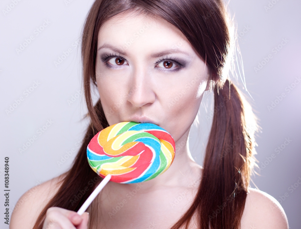 Beautiful girl with brown hair, glamorous make-up, fashion style portrait, holding candy in her hand sexy look
