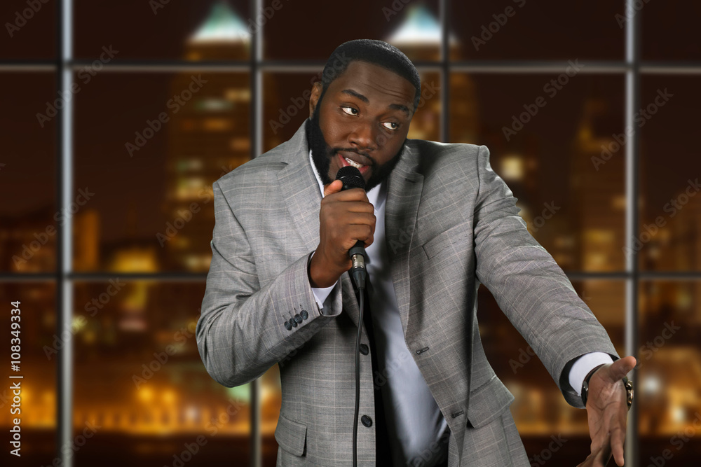 Expressive black man with microphone. Stand-up comedian on night  background. Comedy show on local television. Old funny story. Stock Photo |  Adobe Stock