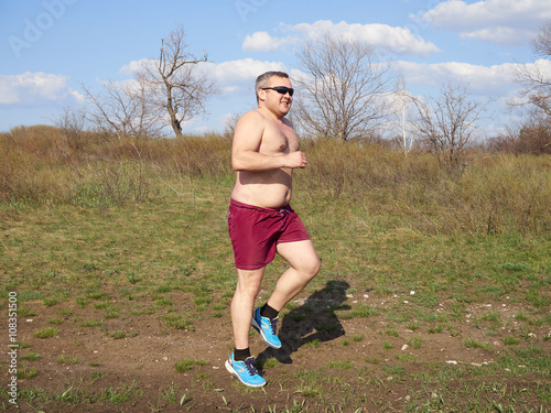 Fat man running outdoors on nature.