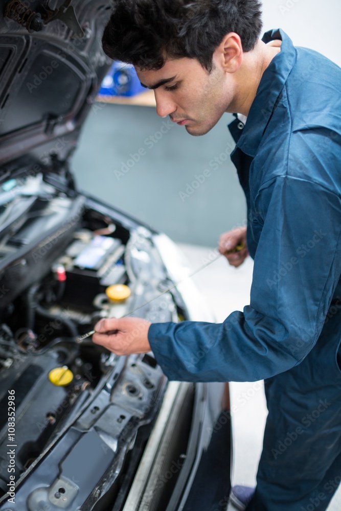 Mechanic checking the oil level in a car engine Mechanic checking the oil level in a car engine