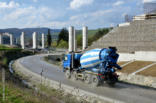 Four axles truck mixer on the road near by highway under construction