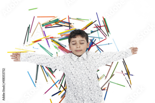 Boy lying on pencils isolated on white background