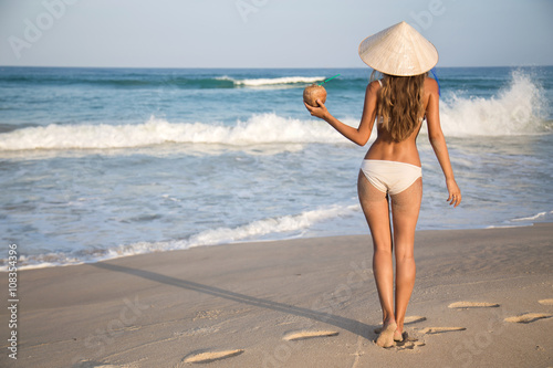 girl in hat on the beach with a cocktail coconut