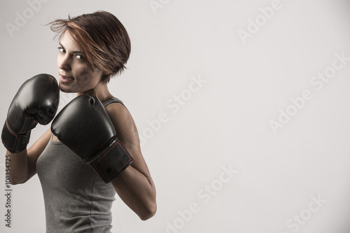 Boxer donna con guanti da box sta in posizione di guardia sinistra e sguardo di sfida photo