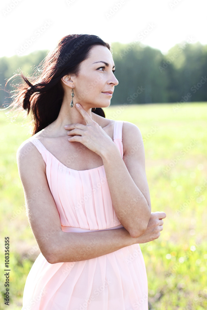 Beautiful woman standing in a field pink dress, fashion style, the concept of portrait outdoor Beautiful woman standing in a field pink dress, fashion style, the concept of portrait outdoor