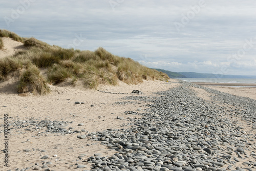 low down shot of beach with pebbles and grassy dunes in Ynyslas, Wales, UK
