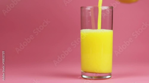 Orange juice in glass and bottle on pink background