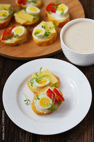 Sandwiches with quail eggs, cheese and pepper. Milk coffee.