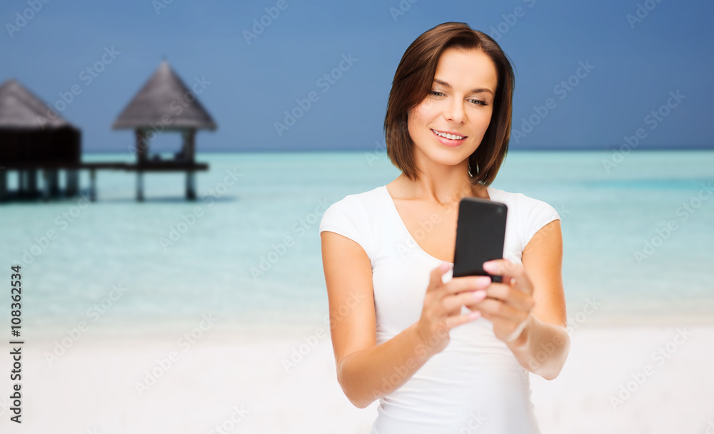 happy woman taking selfie by smartphone over beach