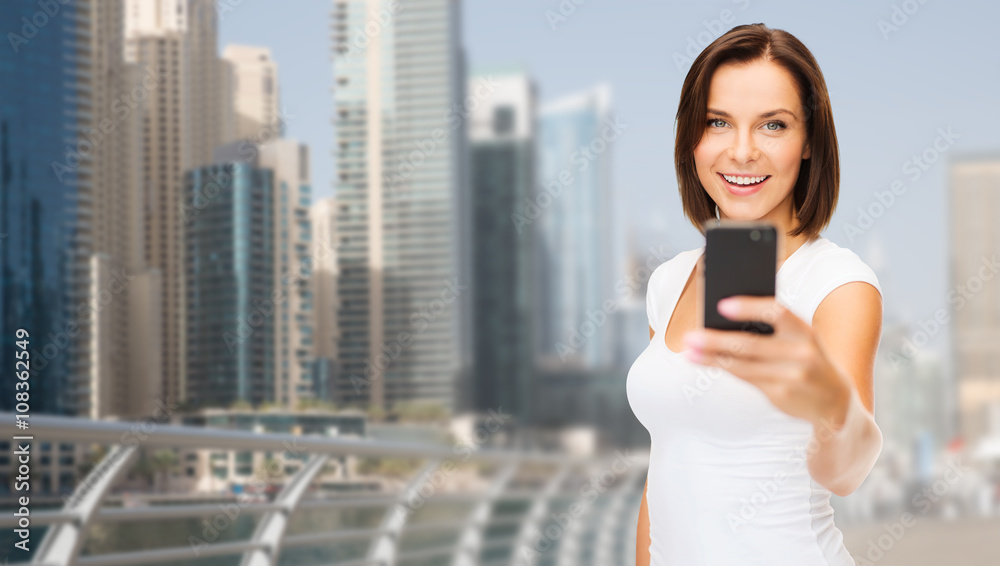 woman taking picture by smartphone over dubai city woman taking picture by smartphone over dubai city