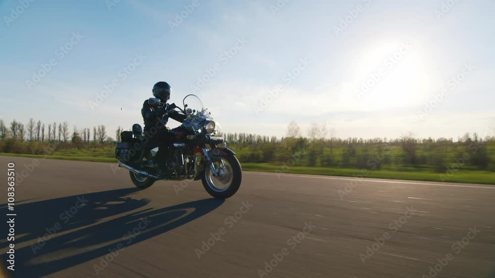Biker rides along green field Biker rides along green field