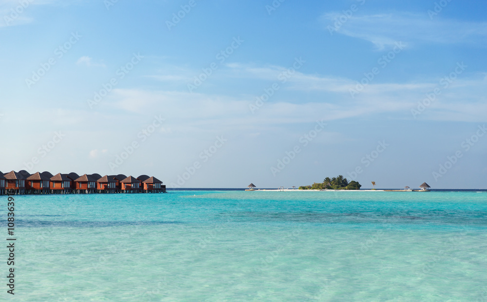 bungalow huts in sea water on exotic resort beach
