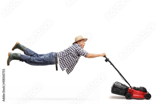 Mature gardener being pulled by a lawn-mower