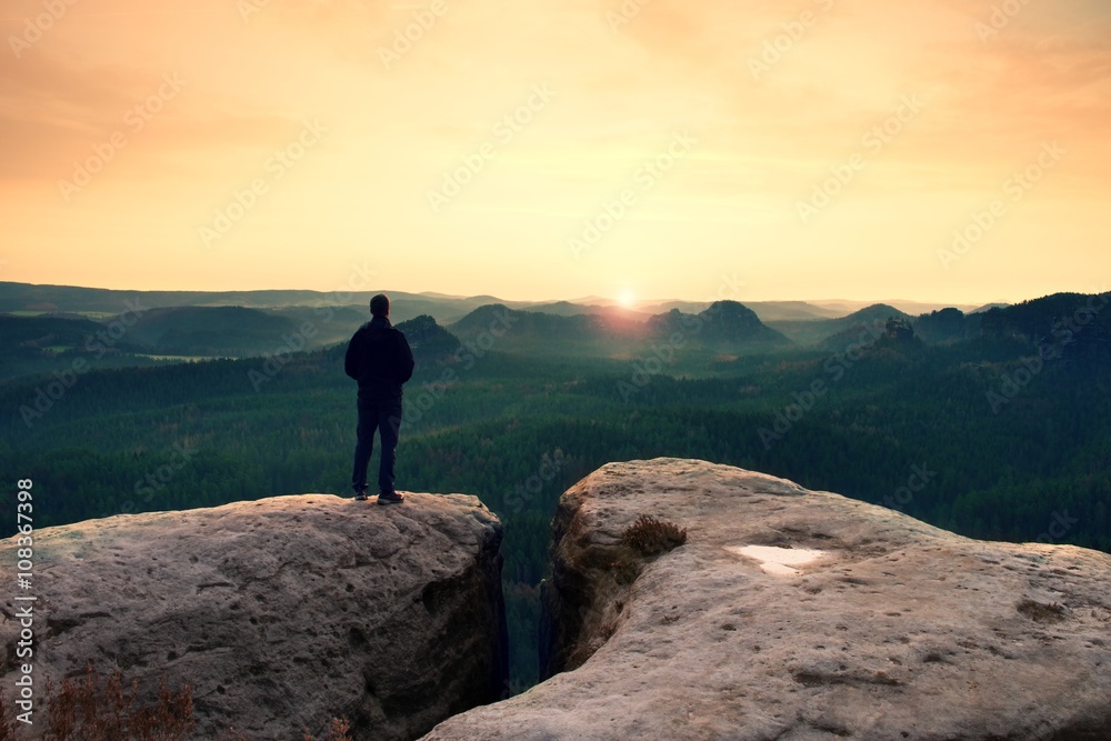 Hiker on sharp cliff in rocky empires park, watching over misty and foggy morning gulch to horizon.