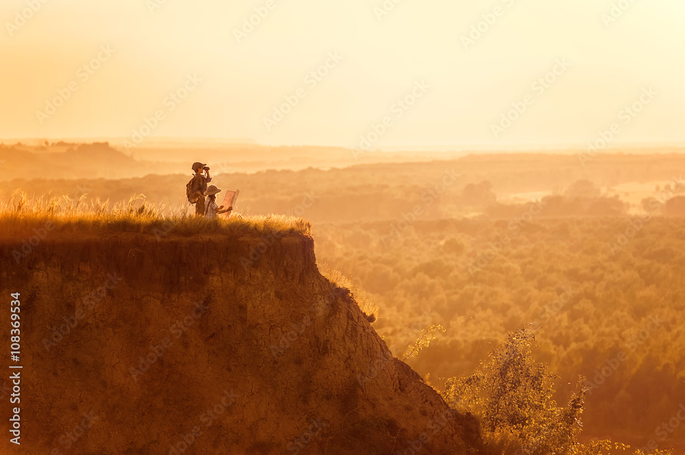 Children with tourists on a cliff at sunset