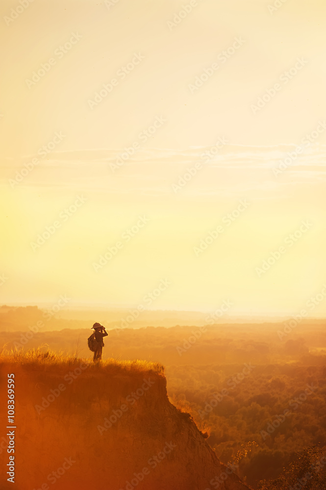 Boy with tourist on a cliff at sunset
