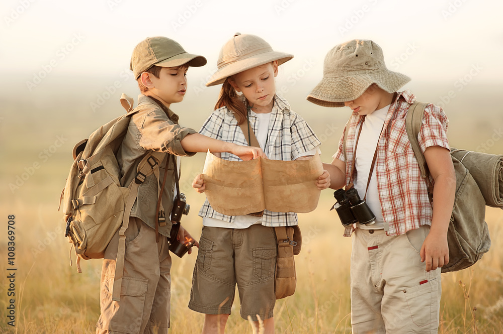 Group of kids travelers read a map at sunset