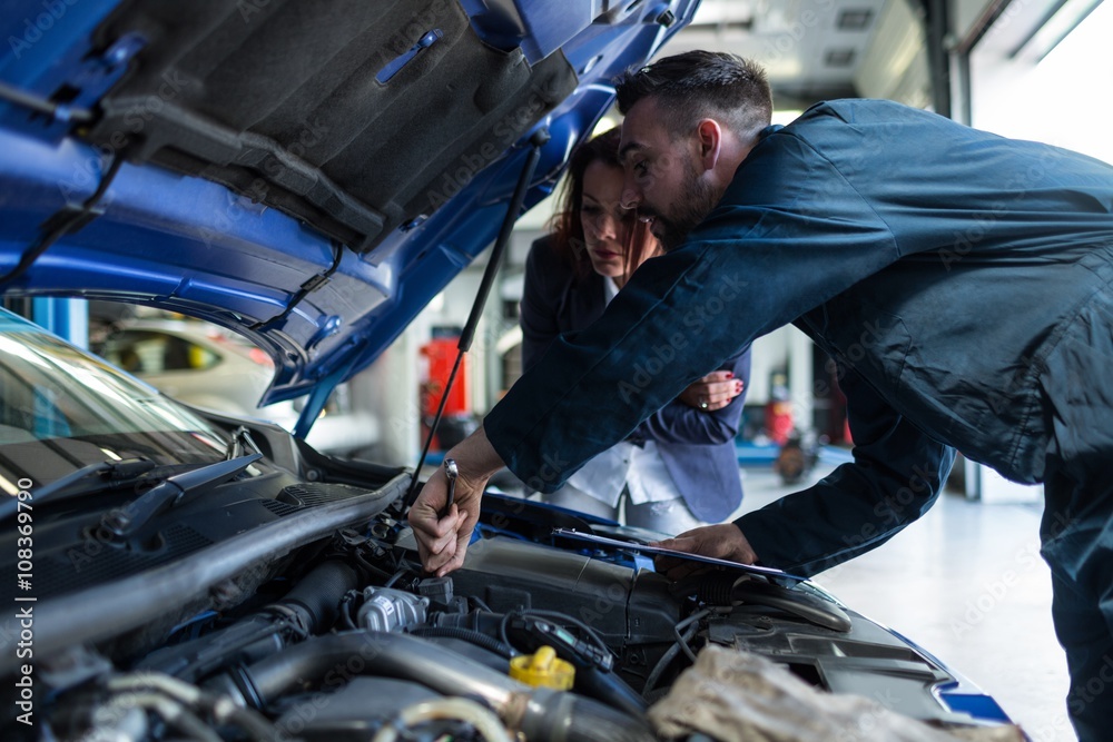 Mechanic showing customer the problem with car Mechanic showing customer the problem with car